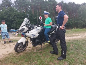 dziecko siedzące na motocyklu policyjnym, obok policjant
