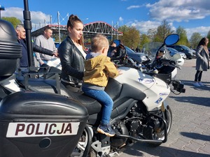 dziecko siedzące na motocyklu policyjnym , obok stojąca kobieta