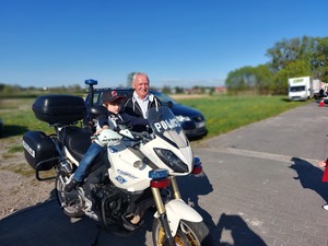 dziecko siedzące na motocyklu policyjnym, obok stojący mężczyzna