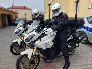 Policjanci w kombinezonach i kaskach siedzący na motocyklach