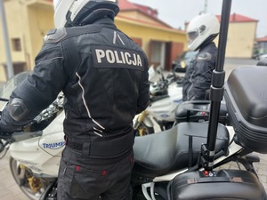 Policjanci w kombinezonach i kaskach siedzący na motocyklach