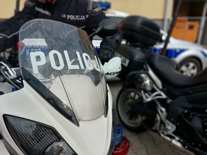 Policjanci w kombinezonach i kaskach siedzący na motocyklach