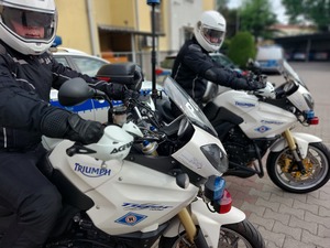 Policjanci w kombinezonach i kaskach siedzący na motocyklach