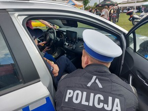 policjant nachylający się nad radiowozem