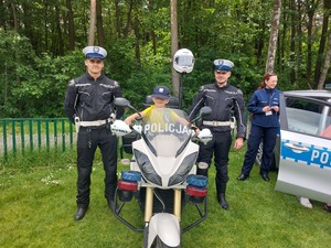 policjanci stojący obok motocykla na którym siedzi dziecko