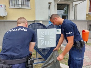 policjanci napełniający worki nakrętkami, obok niebieskie serce