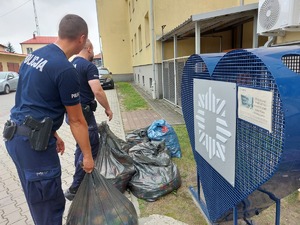 policjanci napełniający worki nakrętkami, obok niebieskie serce