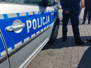 radiowóz, w tle stojący policjant