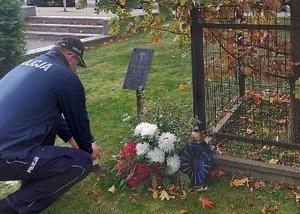 policjanci stojący przed dębem pamięci oraz przed grobem