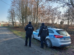 dwóch policjantów idących obok radiowozu