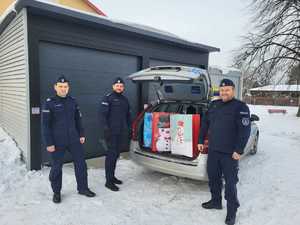 policjanci obok radiowozu, w otwartym bagażniku radiowozu widać torby z prezentami