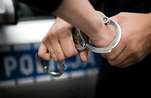 Policjant zakłada zatrzymanemu kajdanki