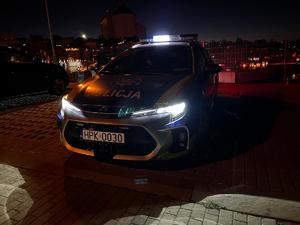 Radiowóz policyjny nocą obok cmentarza