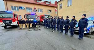 Policjanci stoją ustawieni w szeregu wspólnie ze strażakami.