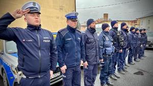 Policjanci stoją ustawieni w szeregu wspólnie ze strażakami.